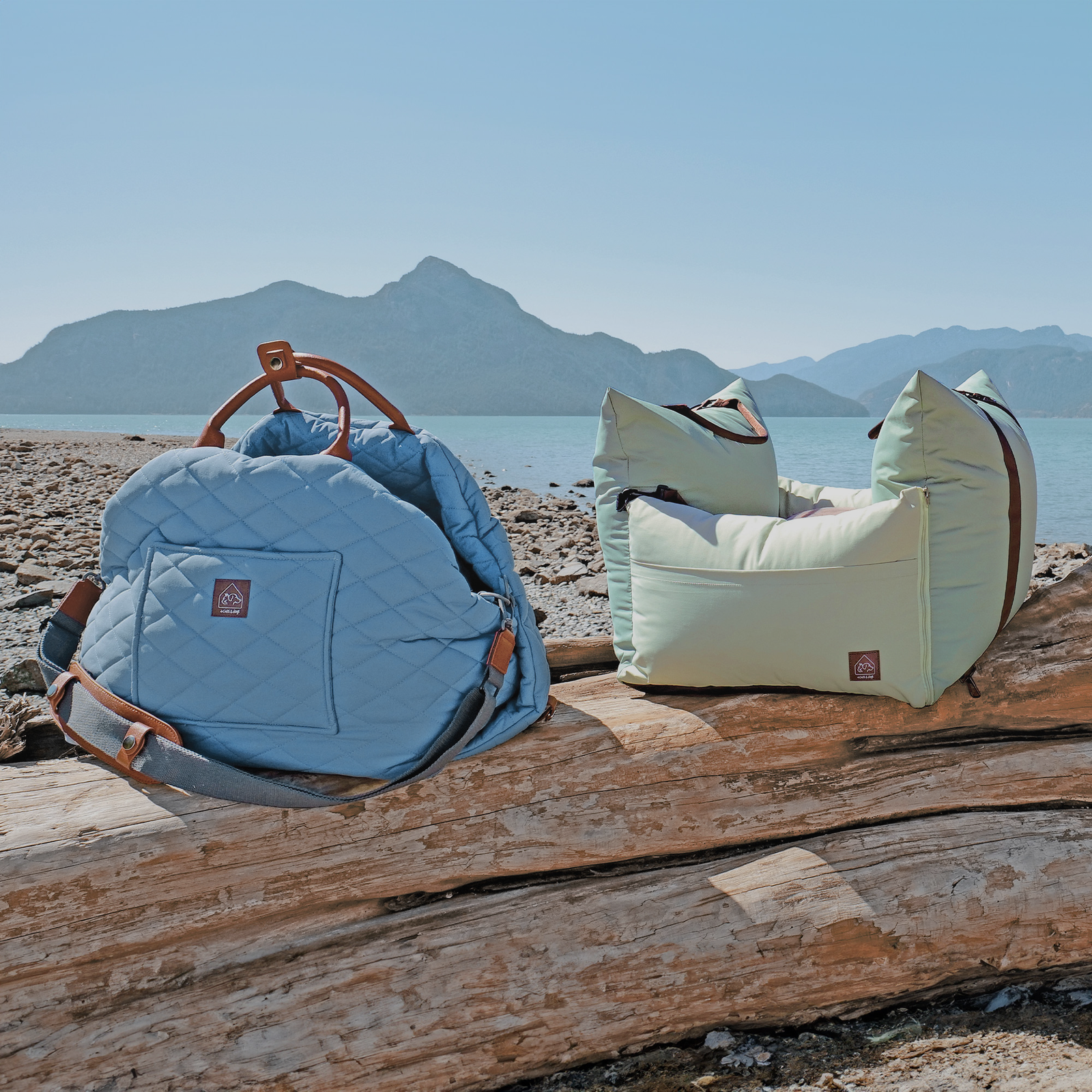 Two fashionable bags on a log near the water, designed for pet-friendly travel and stylish lounging.